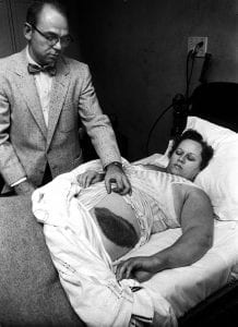 Stars Fell on Alabama: Black and white photograph of a woman lying in bed, a doctor at her side, holding the bedclothes back to show off a huge black bruise about 30cm long and 15cm wide.